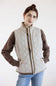 A woman modeling a quilted zip-front vest over a brown long-sleeve shirt and blue jeans, photographed against a plain light background.