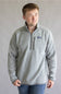 A man wearing a heather gray quarter-zip fleece pullover with a small Patagonia logo on the left chest, paired with blue jeans, standing against a neutral gray studio background.