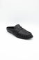 A single black leather loafer-style mule shoe with a decorative strap across the vamp, photographed on a clean white studio background.