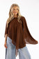 A woman modeling a brown sheer poncho-style top with wide draped sleeves and an asymmetrical hem, paired with light blue jeans and a patterned headband against a plain white background.