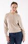 A woman wearing a light beige knit sweater with a buttoned henley-style neckline and dark blue jeans, standing against a plain white studio background.