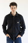 A man wearing a long-sleeve Carhartt plaid button-up shirt in navy and brown with thin orange stripes, paired with blue jeans, against a plain white background.