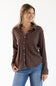 A woman wearing a brown ribbed long-sleeve button-up shirt and blue jeans, standing against a plain white studio background.