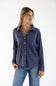 A woman wearing a dark blue ribbed long-sleeve button-up shirt and blue jeans, standing against a plain white background.