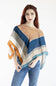 A woman with red hair wearing a multi-colored patterned poncho top and blue jeans, standing against a plain white background.