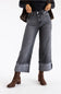 A person wearing dark gray cropped jeans with rolled cuffs showing a paisley pattern, styled with brown ankle boots and a dark jacket against a plain white studio background.