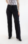 A model wearing a pair of black wide-leg denim jeans, styled with a sheer white patterned long-sleeve top and black pointed-toe heels, against a plain white studio background.