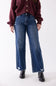 Front close-up view of a model wearing KanCan dark wash, high-rise wide-leg jeans with slight distressing at the hem and thighs, styled with black boots and a button-front burgundy sweater against a plain backdrop.