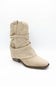 A single beige suede slouchy ankle boot with a low brown block heel, shown from a side profile on a white background.