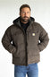 A man wearing a brown Carhartt hooded puffer jacket over a black shirt and blue jeans, standing against a light gray studio background.