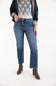 A model wearing a pair of dark-wash blue straight-leg jeans, styled with a white lace top, a dark navy jacket, and brown ankle boots, set against a plain white studio background.