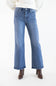 A person wearing medium-wash blue wide leg jeans with a white ribbed sweater and brown heeled ankle boots, shown from the waist down against a plain white studio background.