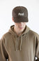 A man wearing a brown trucker hat with 'Marsh Wear' embroidered in white on the front, paired with a brown hoodie, against a plain white background.