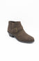 A single women's ankle boot in dark brown suede, featuring a matching brown strap across the instep with a gold-tone buckle, set against a plain white background.