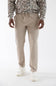 A person wearing beige drawstring jogger pants, a camouflage-patterned long-sleeve shirt, and white sneakers, photographed against a clean white studio background.