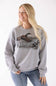 A woman wearing a heather gray crewneck sweatshirt with a detailed graphic of mallards on the front, paired with blue jeans, against a plain white background.