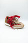 A low-top sneaker featuring a beige suede upper with a red and black leopard print overlay, red laces, and a white midsole with a gum outsole, shown on a light gray background.