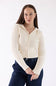 A woman modeling a cream ribbed knit zip-up hooded sweater with front pockets, paired with dark blue jeans, against a plain white studio background.