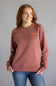 Dark red colored sweatshirt with orange Carhartt cursive letters on chest