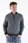 A smiling male model wearing the F/X Fusion Birdseye Knit Quarter Zip in nickel gray, featuring a mock neck, quarter-zip placket, and dark contrasting trim along the collar, cuffs, and hem, paired with classic denim jeans.