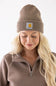 Blonde modeling a brown cuffed Carhartt beanie with carhartt logo on cuff