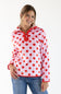 A woman modeling a pink hooded quarter-zip fleece pullover with red polka dots and red trim, paired with blue jeans, against a plain white studio background.