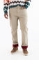 A person wearing beige straight-leg pants with red and black plaid cuffs, paired with brown lace-up shoes and a patterned knit sweater, shown from the chest down on a white background.
