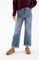 A person wearing light blue wide-leg distressed jeans with cuffed hems, paired with a dark burgundy sweater and tan slip-on shoes, shown against a plain white studio background.
