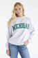 A woman modeling a light heather gray crewneck sweatshirt with 'MICHIGAN' printed in green varsity lettering across the chest, paired with blue jeans against a plain white background.