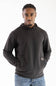 Model wearing a dark raven black long-sleeve hooded sweatshirt featuring a crossover neckline, front kangaroo pocket, small woven brand patch near the hip, paired with blue jeans against a white background.