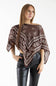 A woman modeling a brown and white patterned poncho top with black faux-leather pants, photographed against a plain white studio background.