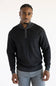 A man wearing a dark charcoal gray quarter-zip sweater with light gray piping details on the collar and cuffs, paired with light gray trousers, against a plain white studio background.