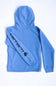 A light blue Carhartt hoodie shown from the back, featuring the brand's name and logo printed in black along the left sleeve, laid flat on a white background.