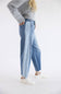 A model wearing light-wash wide-leg blue jeans, a gray ribbed knit sweater, and white sneakers, standing against a plain white studio background.