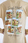 A beige t-shirt featuring a back graphic print with six postage stamp illustrations of Highland cows and the text 'Simply Blessed' and 'simply southern COLLECTION'.
