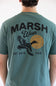 A man viewed from behind wearing a teal green t-shirt with a large black graphic on the back reading 'MARSH Wear' and 'EST. 2010 USA', featuring a flying duck and a circular gold emblem.
