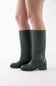 Dark green knee-high leather boots with low block heels, shown on a model's feet against a plain white studio background.
