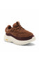A brown textured sneaker with a chunky off-white sole, featuring a fuzzy sherpa-like upper, dark brown suede overlays, and a small yellow Vibram logo on the side.
