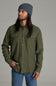 A man wearing an olive green button-down shirt with chest pockets, blue jeans, and a gray beanie, photographed against a solid gray studio background.