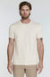 A man wearing a plain cream-colored short-sleeve crewneck t-shirt and khaki pants, standing against a light gray studio background.