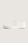A single white slip-on platform sneaker with a subtle embossed pattern on the upper, shown in profile against a solid light beige background.