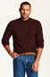 A man wearing a dark burgundy knit crewneck sweater, blue jeans, and a brown braided belt, standing against a plain off-white background.