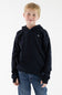 A young boy with blonde hair wearing a dark navy blue hooded sweatshirt with a small embroidered moose logo on the left chest, paired with blue jeans, standing against a plain white studio background.