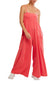 Woman wearing a coral pink jumpsuit on a white background