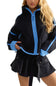 A woman wearing a black sherpa fleece zip-up jacket with bright blue trim and a black pleated mini skirt, photographed against a plain white background.