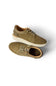 A pair of low-top suede sneakers in a muted olive-tan color, featuring matching laces and thick off-white soles, shown from a top-down angle on a white background.