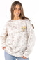 A woman wearing a light beige and white tie-dye sweatshirt with a small graphic of cowboy boots and flowers on the left chest, paired with blue jeans, against a plain white background.