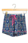 A pair of girls' floral print shorts in navy blue with a pink drawstring and pink piping, hanging from a wooden hanger on a white background.