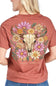 A woman shown from the back wearing a rust-colored short-sleeve t-shirt with a large graphic print of a steer skull surrounded by pink, yellow, and white flowers. The text 'simply southern' is printed below the graphic.