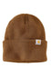 A brown waffle-knit beanie hat with a folded cuff and a small white Carhartt logo patch on the side, shown against a plain white background.